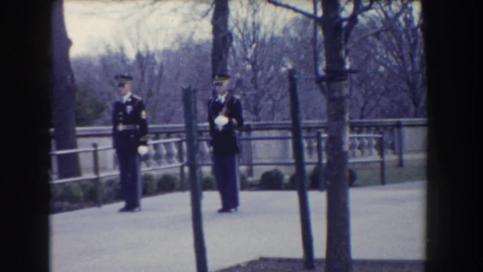 Washington, DC 1960 home-movie frame showing two Marines in dress uniforms moving in a synchronized ceremonial march.
