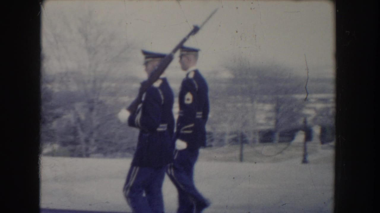 Two soldiers in dark dress uniforms and white gloves march with rifles and fixed bayonets in Washington, DC archival footage.