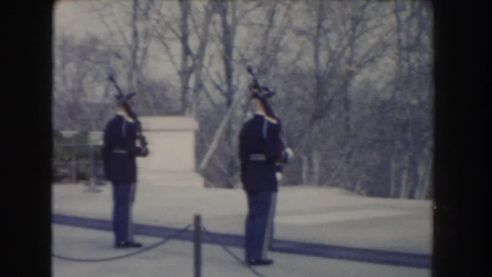 Washington, D.C. 1960 footage shows two military guards in dark uniforms standing near a monument in a winter outdoor setting.