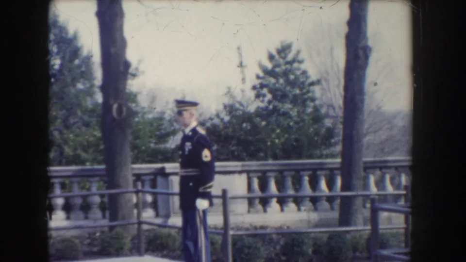 1960 Washington, DC home-movie frame showing a uniformed guard in white gloves standing outdoors by a balustrade.