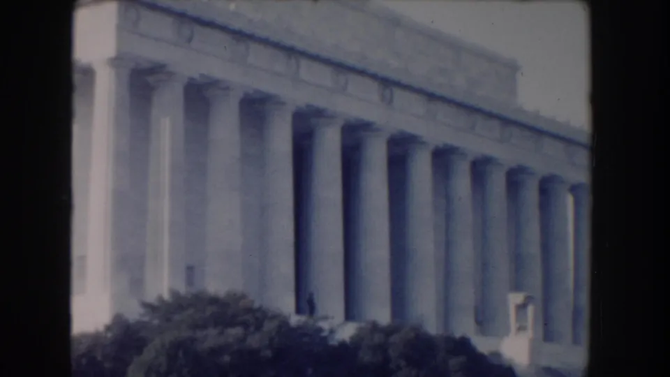Washington, DC view of the Lincoln Memorial's columns, steps, and foreground shrubs in faded color 8mm footage.