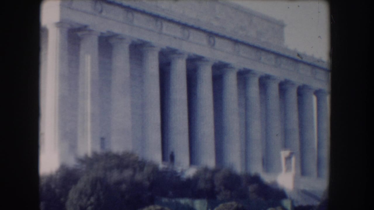 Soft 8mm view of the Lincoln Memorial columns with trees in the foreground.