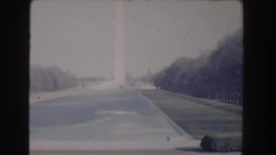 1960 Washington, DC frame showing the Reflecting Pool and Washington Monument from a distant, softly exposed home-movie viewpoint.