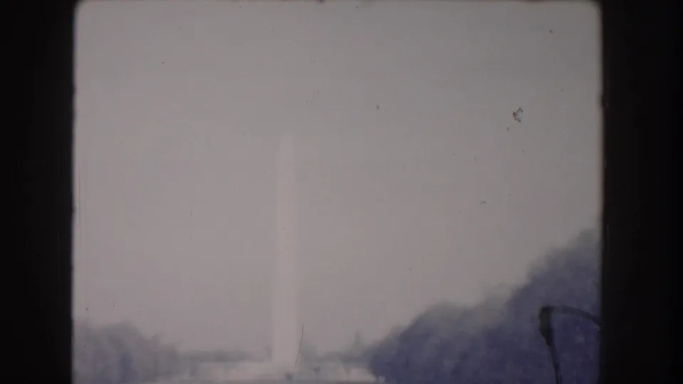 Faded 1960 Washington, DC home-movie frame with the Washington Monument above tree-lined National Mall grounds.