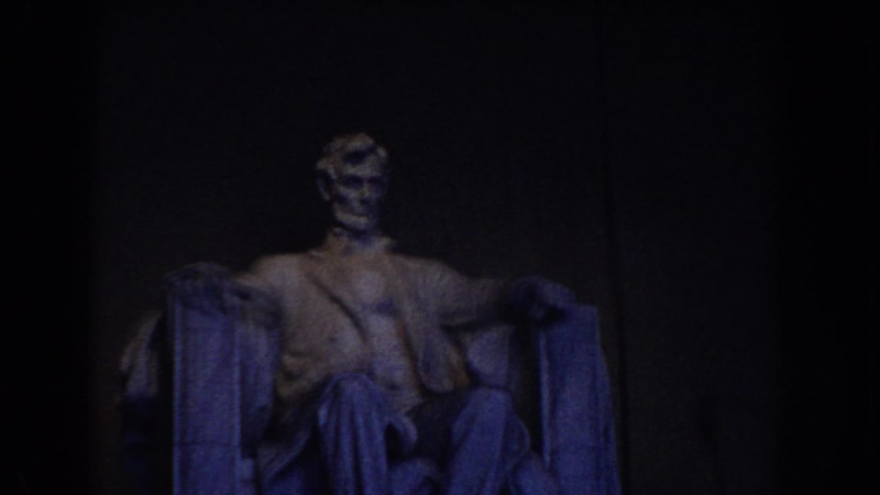 Seated Abraham Lincoln statue in dim blue interior light.