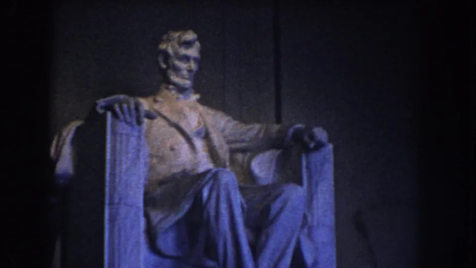 1960 Washington DC frame showing the Lincoln Memorial statue from a slightly rightward visitor perspective in blue interior light.