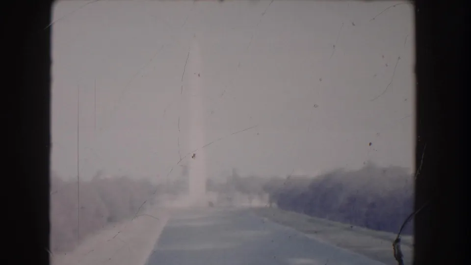1960 Washington, DC home-movie view looking across the National Mall toward the distant Washington Monument through haze, scratches, and faded color.