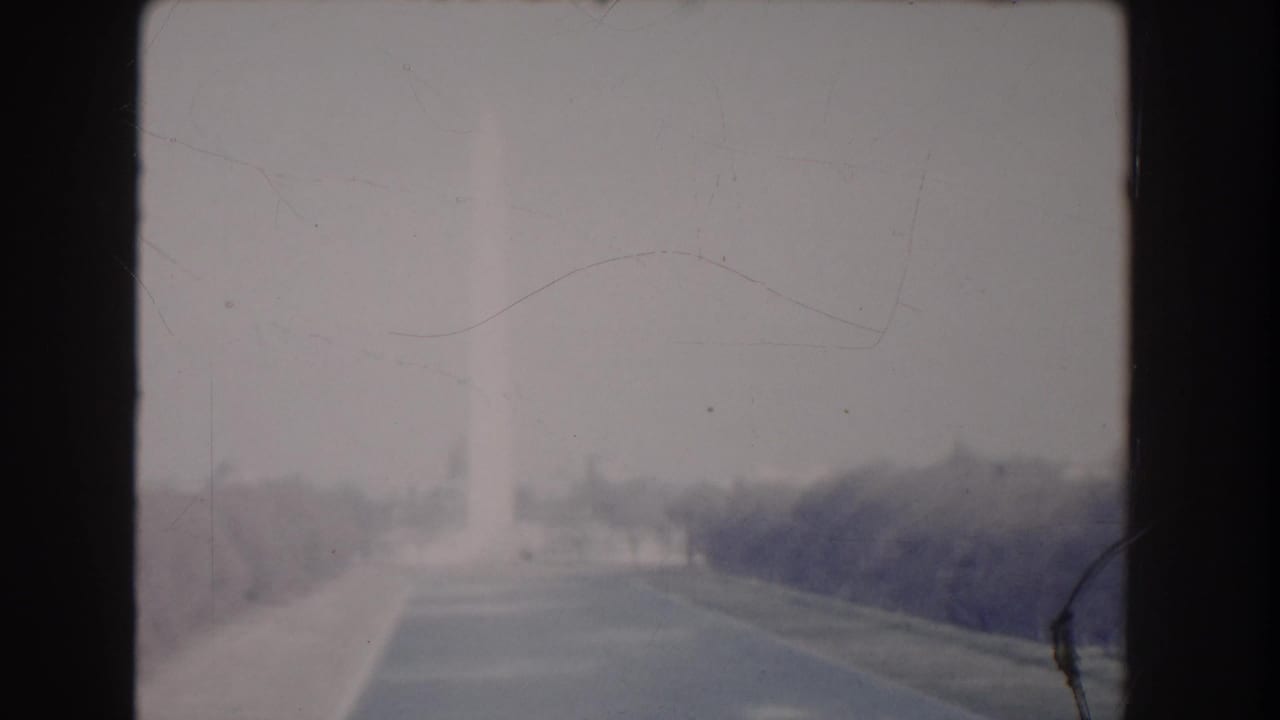 Hazy distant view across a roadway or path with trees and dark 8mm frame edges.