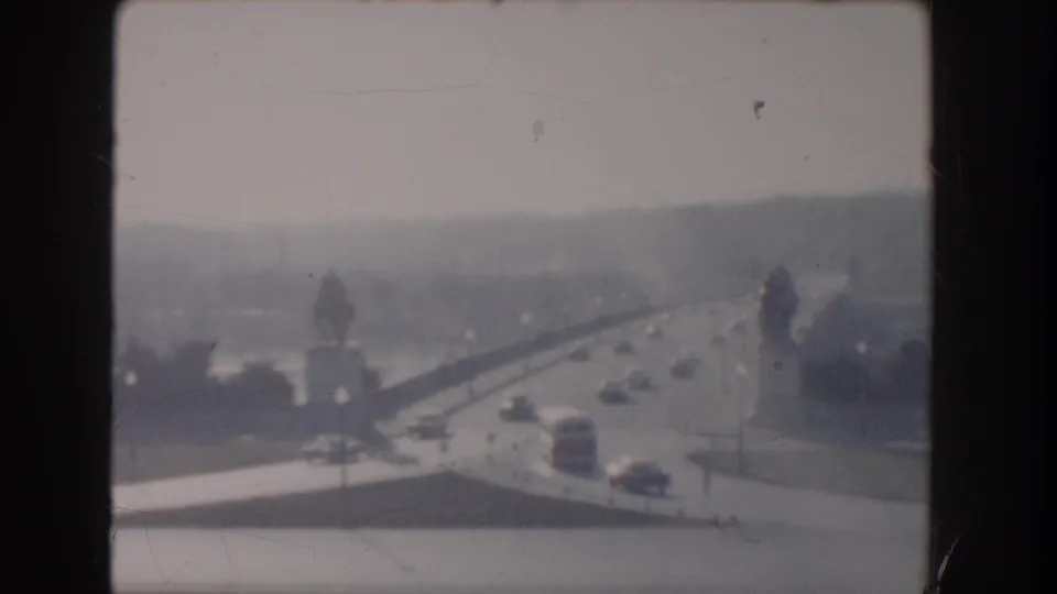 1960 Washington DC 8mm frame showing the Reflecting Pool vicinity with road traffic, trees, and distant monumental forms in haze.
