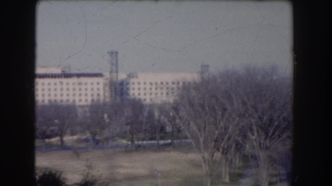 Washington, DC landmark-area view with a long federal-style building partly obscured by bare trees.