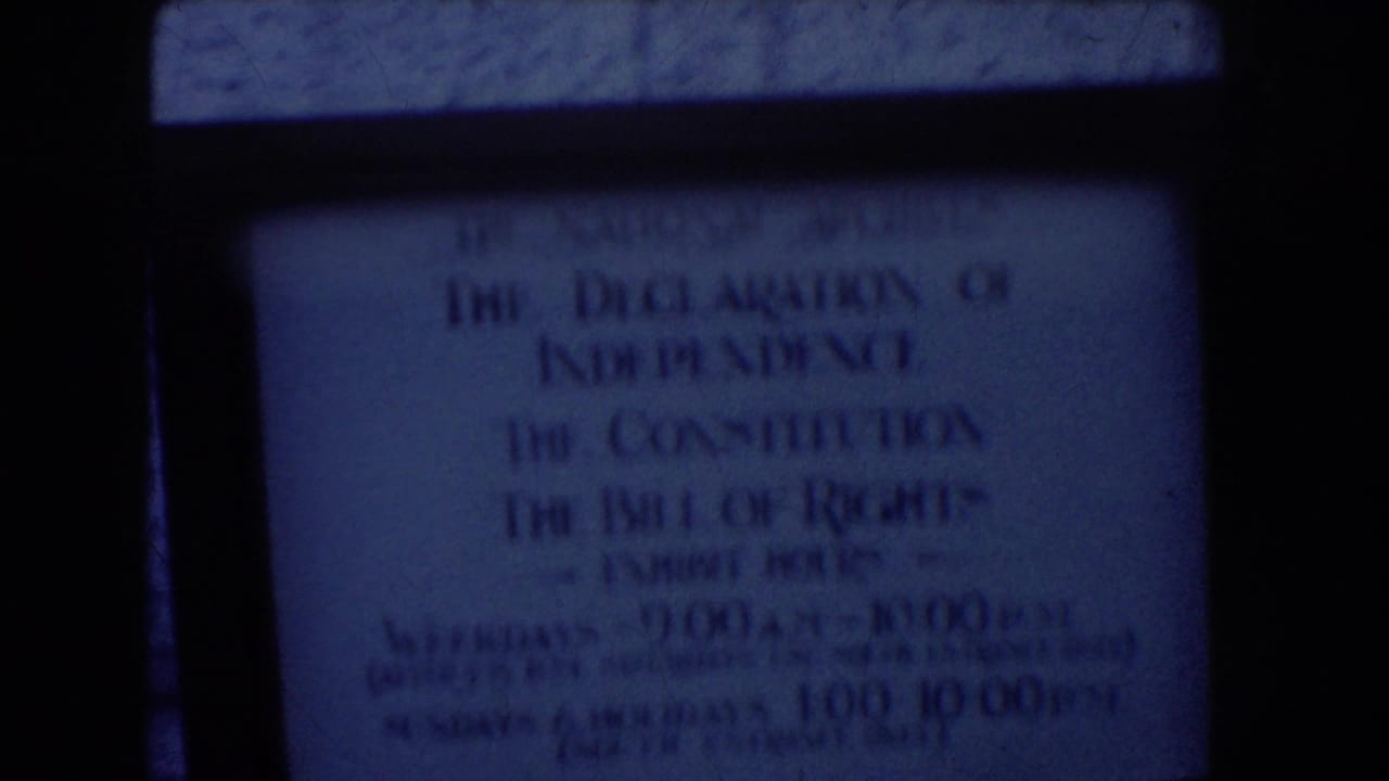 Washington DC 8mm frame showing a dim National Archives sign for the Declaration of Independence, Constitution, and Bill of Rights exhibit.