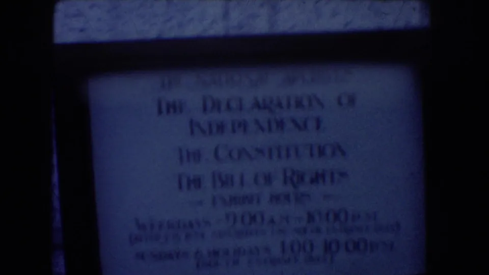 Washington DC 8mm frame showing a dim National Archives sign for the Declaration of Independence, Constitution, and Bill of Rights exhibit.