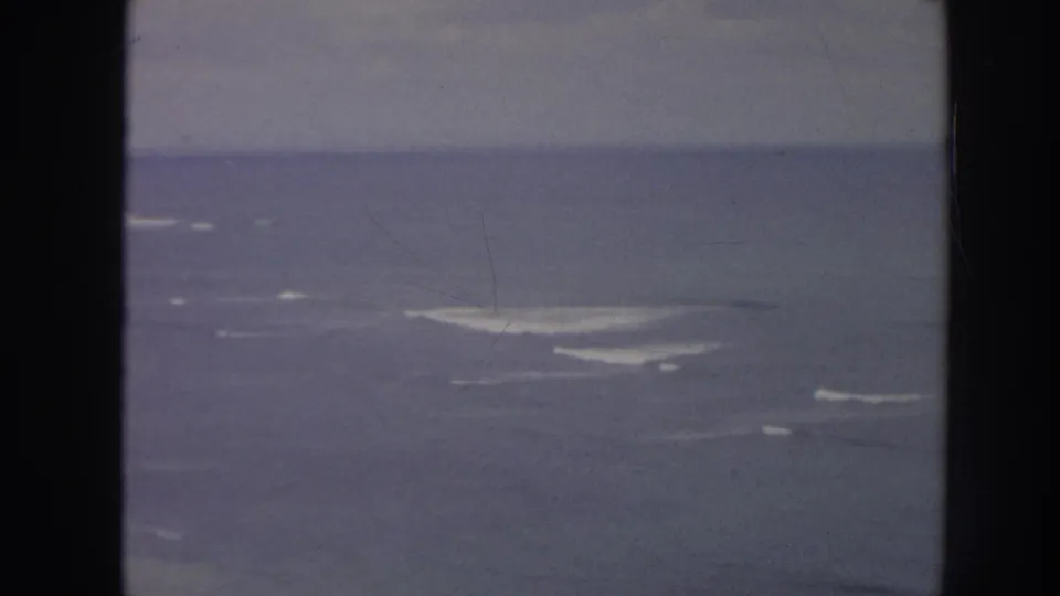 1961 Hawaii coastal frame with open water, scattered whitecaps, a hazy horizon, and dark vertical film-frame edges.