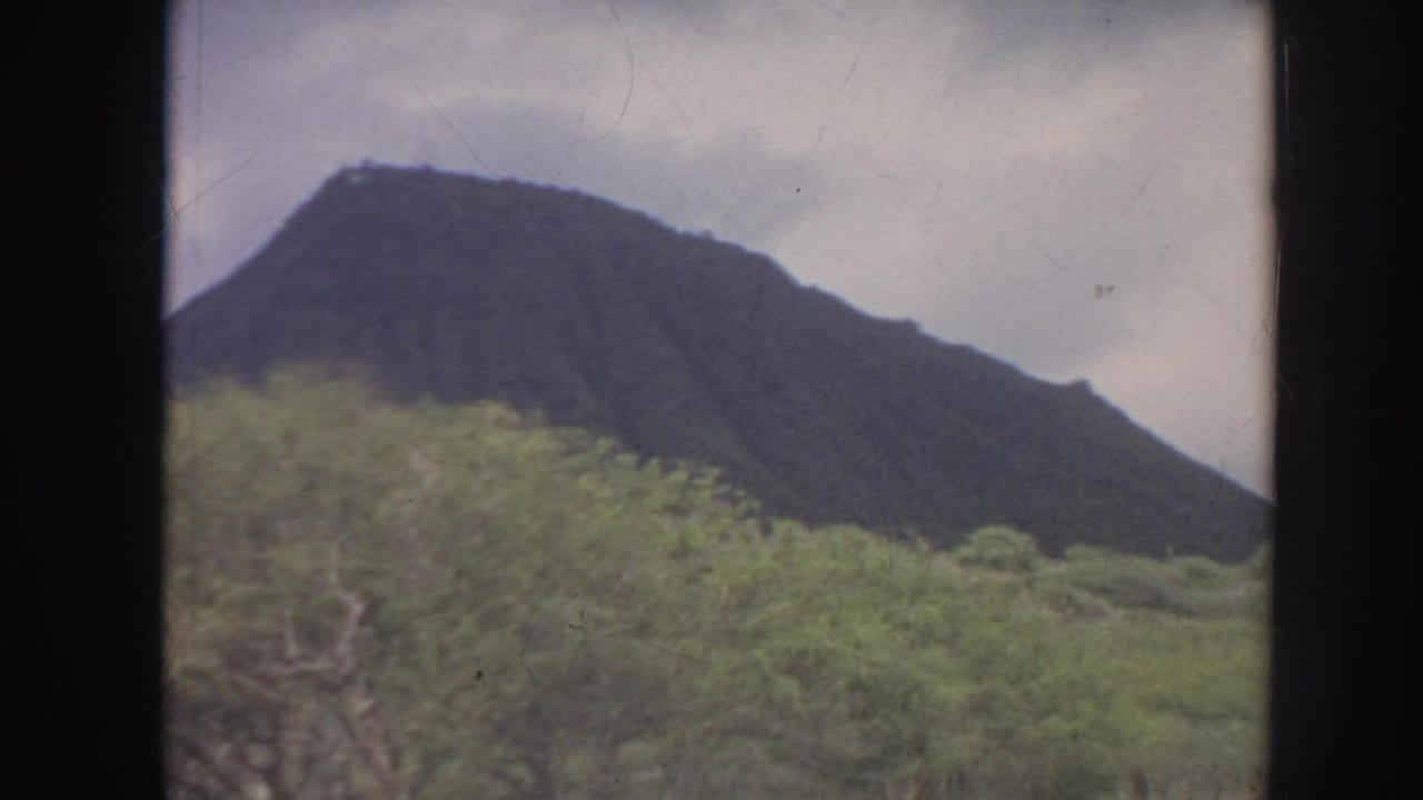 Mountain ridge and green vegetation framed by dark vertical film borders.