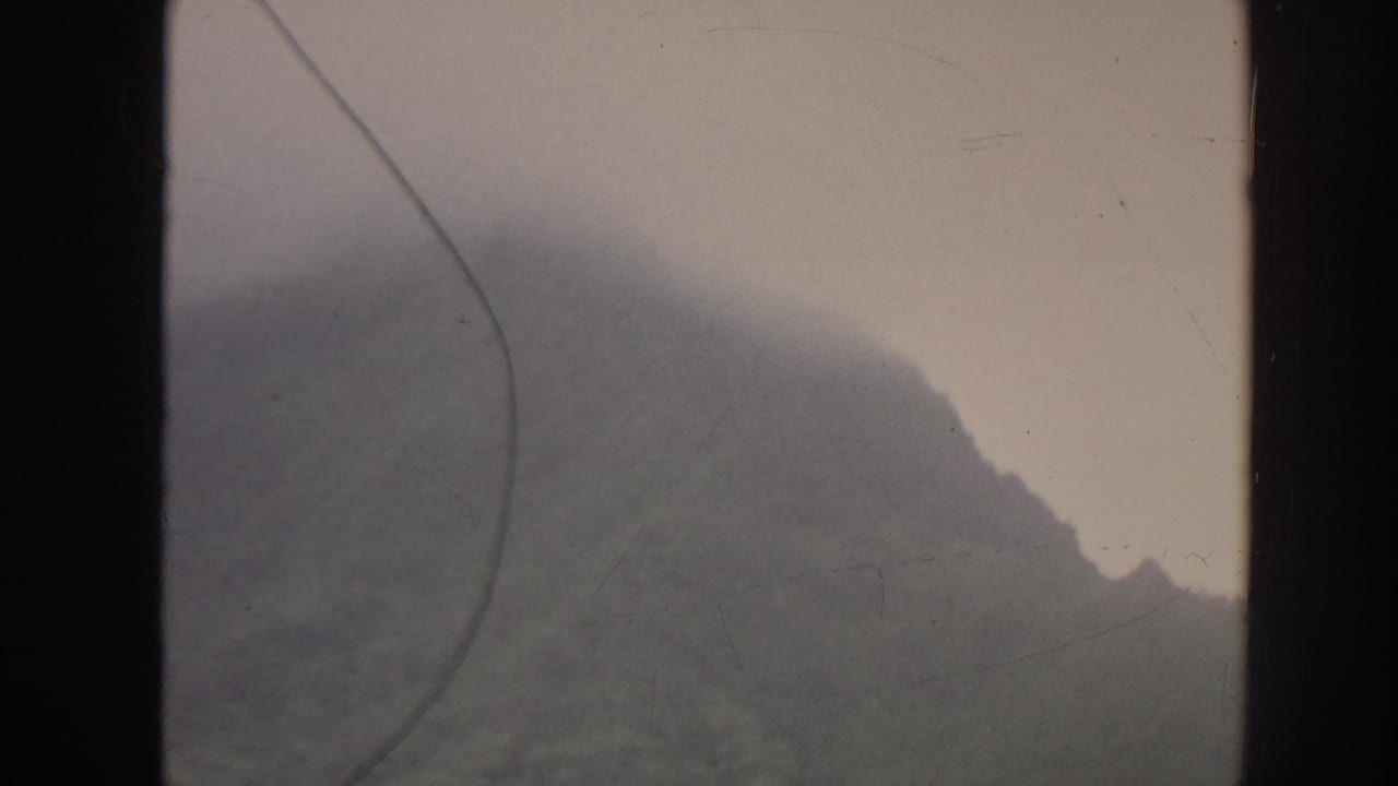 Misty mountain slope framed by dark vertical film edges.