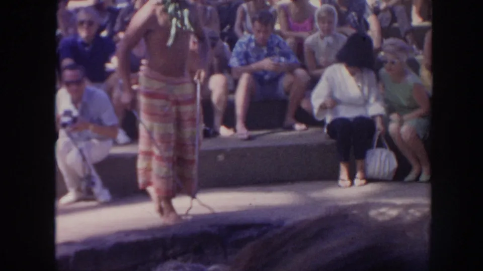 1961 Hawaii home-movie view of a performer in a skirted costume before a seated audience in daylight.