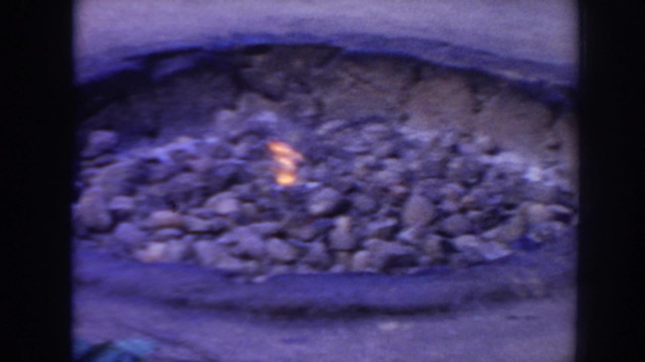 Stone-lined pit with small glowing embers or flame on the ground.