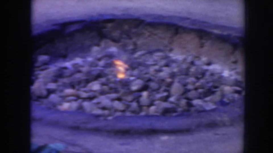 1961 Hawaii 8mm frame showing a stone-lined fire pit with small glowing embers in an outdoor setting.