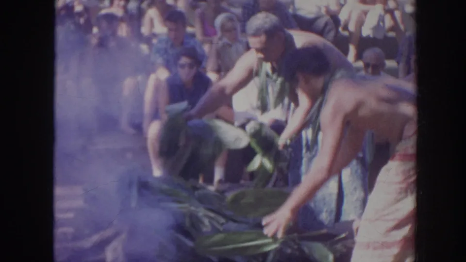 1961 Hawaii home-movie frame showing performers handling banana leaves in front of a close seated audience.
