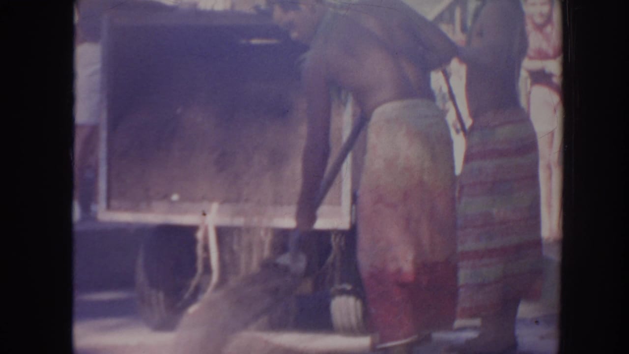 Close view of a wooden box or truck bed with men standing around it.