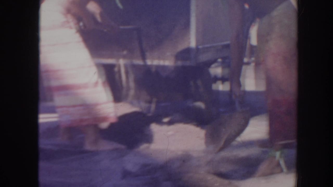 Blurred legs and feet move around a large object on concrete.