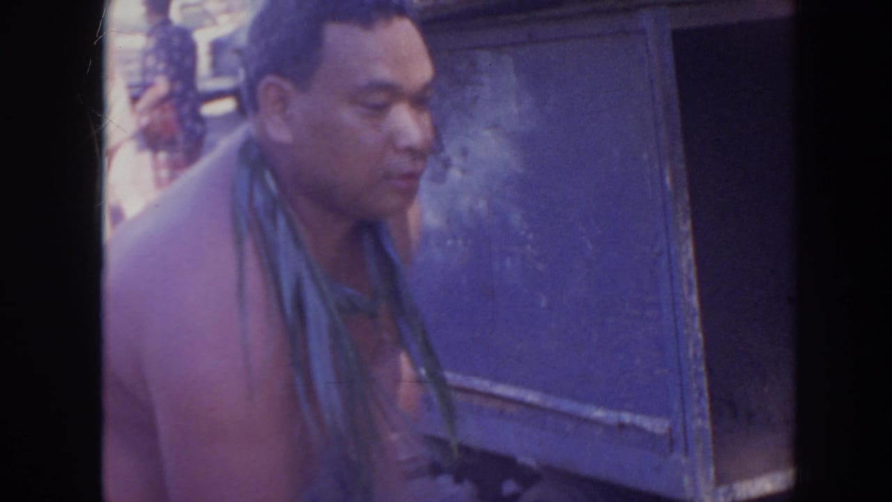 Man with a leaf lei is seen close to a blue utility box.