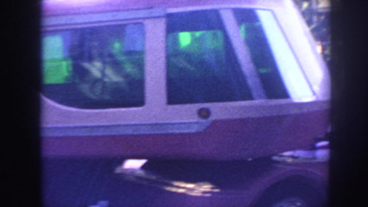 Close view of the front-side section of a pink-and-white bus with windows and dark frame edges.