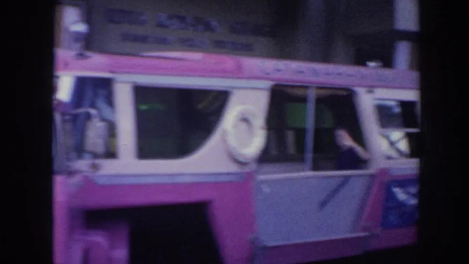 1961 Hawaii 8mm frame showing the bus side, mounted life preserver, open windows, and a person leaning near the window area.