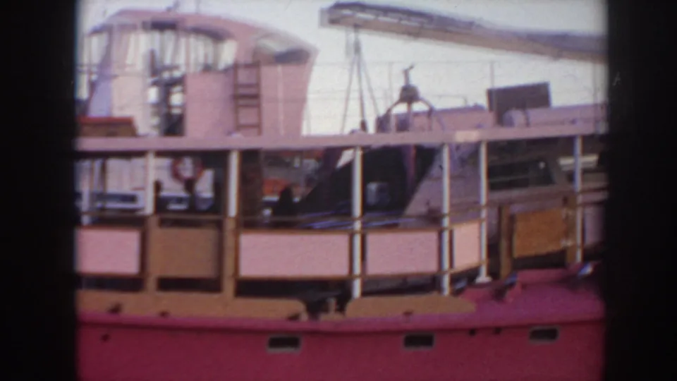 1961 Hawaii 8mm frame of a pink boat's upper decks, with people near the railings and deck equipment in view.