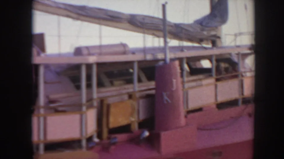 1961 Hawaii 8mm frame of the pink boat's side section, showing a covered deck, railings, windows, and vertical stack detail.