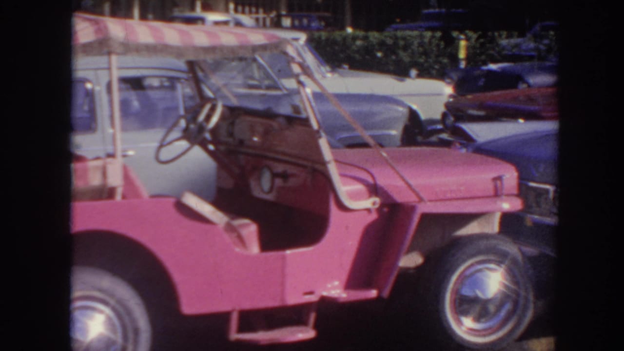 Side view of a pink open-top vehicle with striped canopy and chrome front wheel.