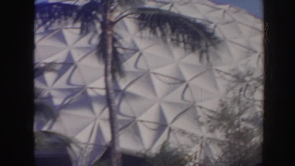 A large geometric dome surface appears behind palm trees and foliage in this 1961 Hawaii home-movie frame.