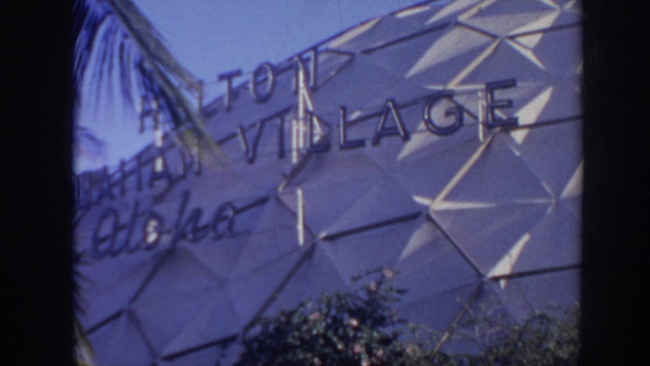 1961 Hawaii home-movie frame showing part of the Hotel Hawaiian Village aloha sign on a geometric exterior facade.