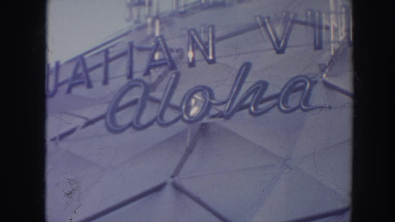 Cropped Hawaiian Village aloha lettering on a pale geometric building facade.