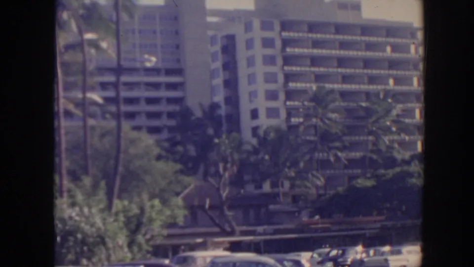 Wide home-movie view of a Hawaii resort hotel exterior with palm trees and multi-story buildings.