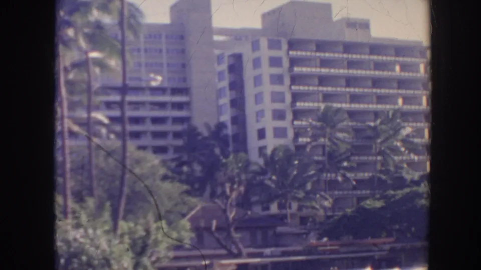 1961 Hawaii resort exterior with high-rise hotel buildings, palms, and landscaped foreground.