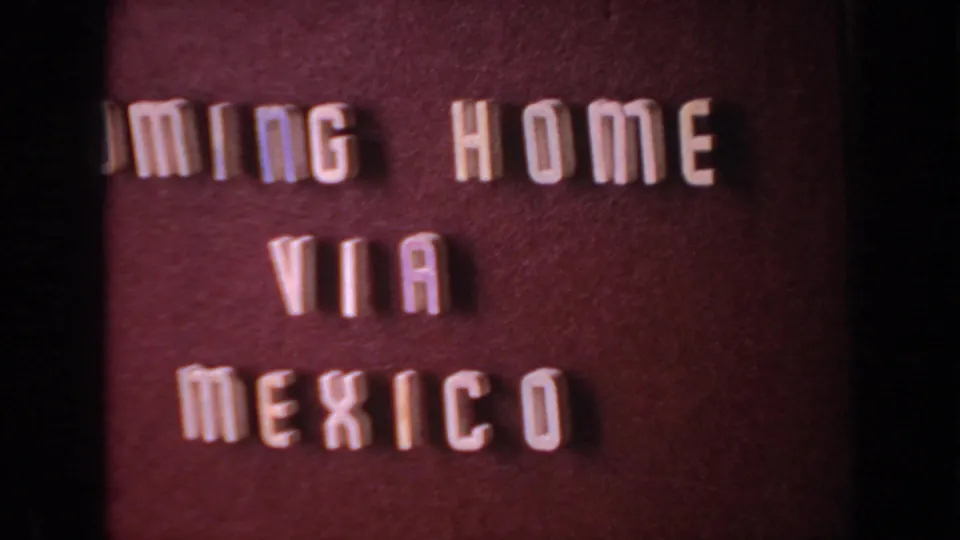 Home-movie title card with white raised lettering reading COMING HOME VIA MEXICO on a reddish background.