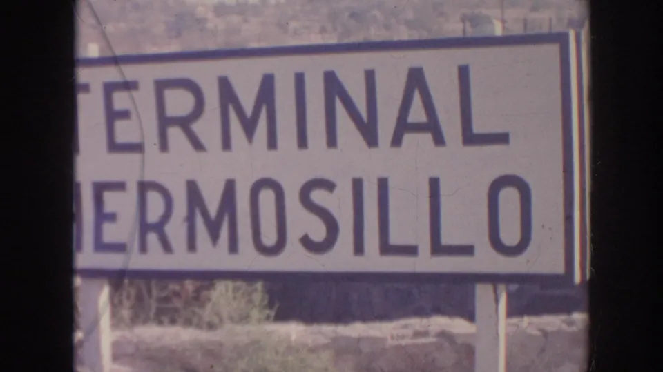 A large outdoor sign appears to read Terminal Hermosillo, cropped by the frame and filmed with visible 8mm wear.