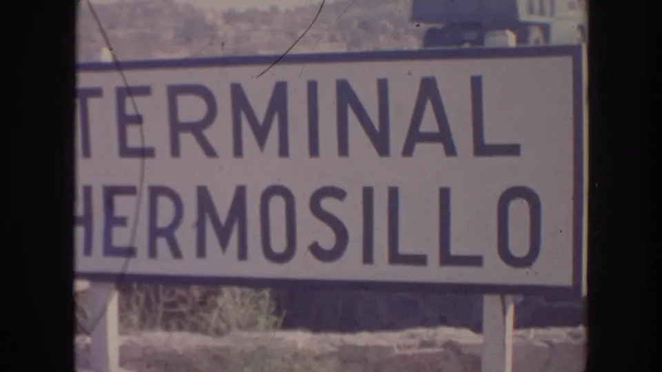 The Terminal Hermosillo sign is more legible, divided by a dark vertical strip and surrounded by sunlit outdoor ground.