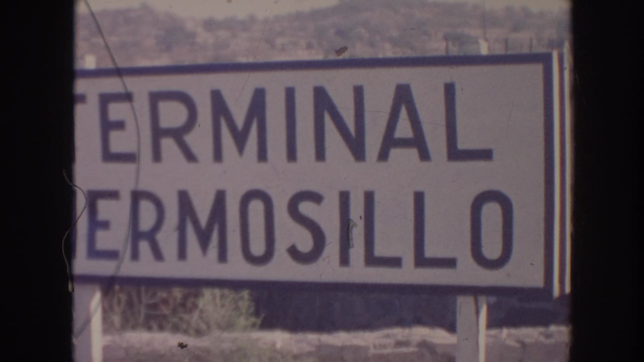 1961 8mm frame showing a close view of a Terminal Hermosillo sign with dry hills behind it.