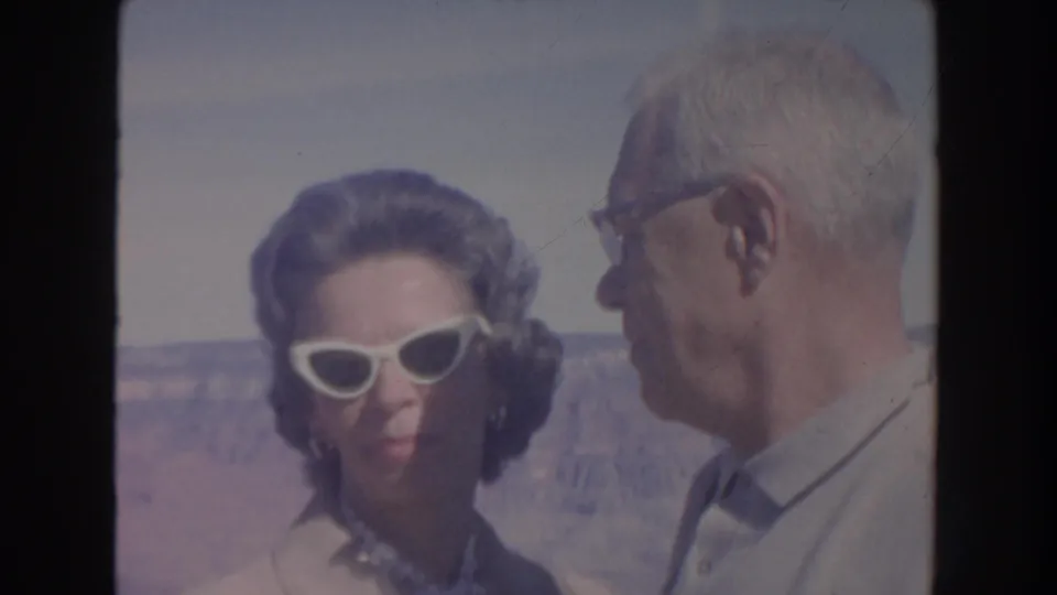 At an Arizona canyon overlook, the woman looks toward the camera as the man turns sideways against the distant landscape.