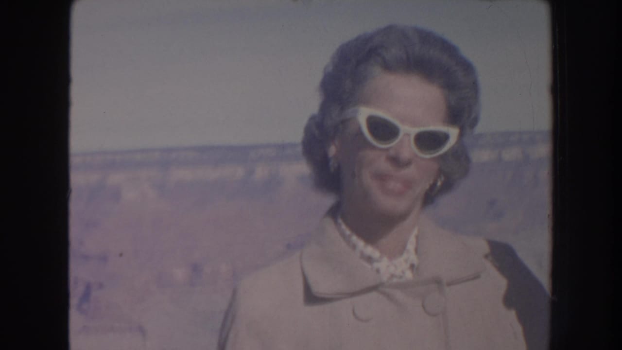 Woman in white cat-eye sunglasses standing before the Grand Canyon landscape.