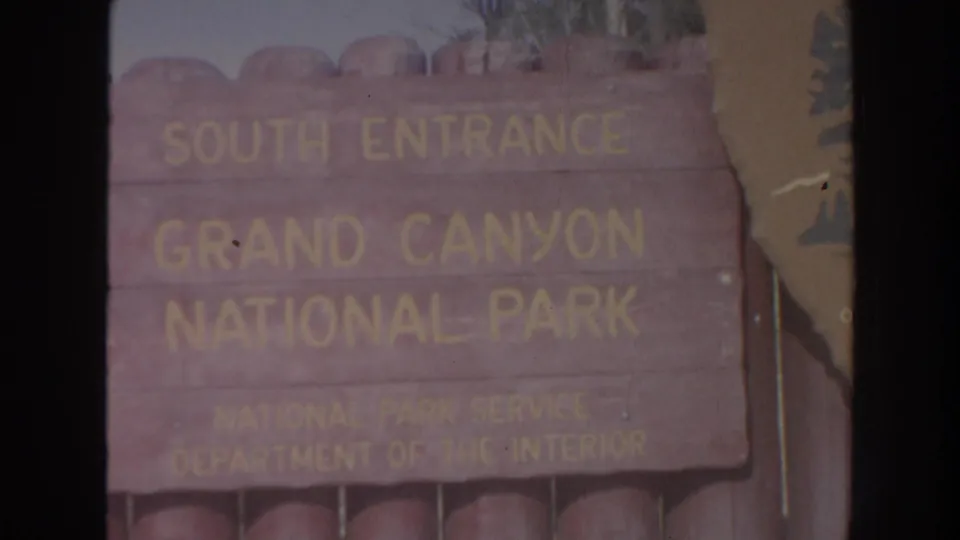 Close 1962 home-movie view of the Grand Canyon National Park South Entrance sign, with faded color and soft 8mm texture.