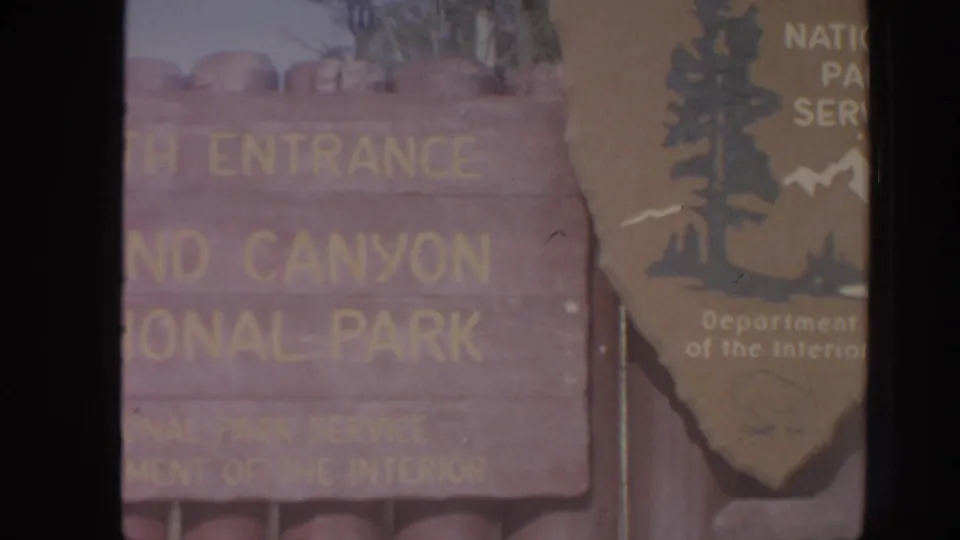 Weathered wooden entrance sign reading Canyon National Park, partly obscured by a National Park Service arrowhead emblem.