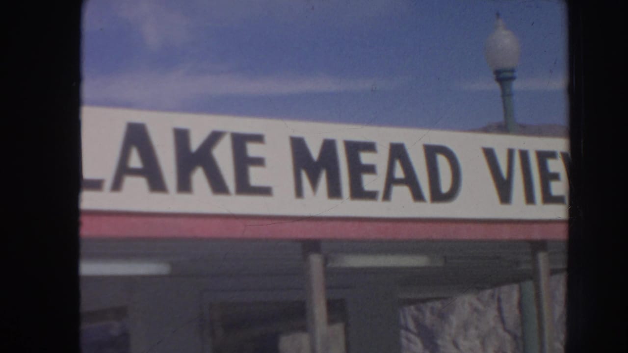 1962 8mm frame of a cropped Lake Mead View storefront sign with a globe streetlamp and blue sky above it.