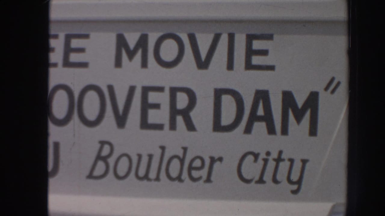 Close 1962 home-movie view of tourist sign lettering for a free movie, Hoover Dam, and Boulder City.