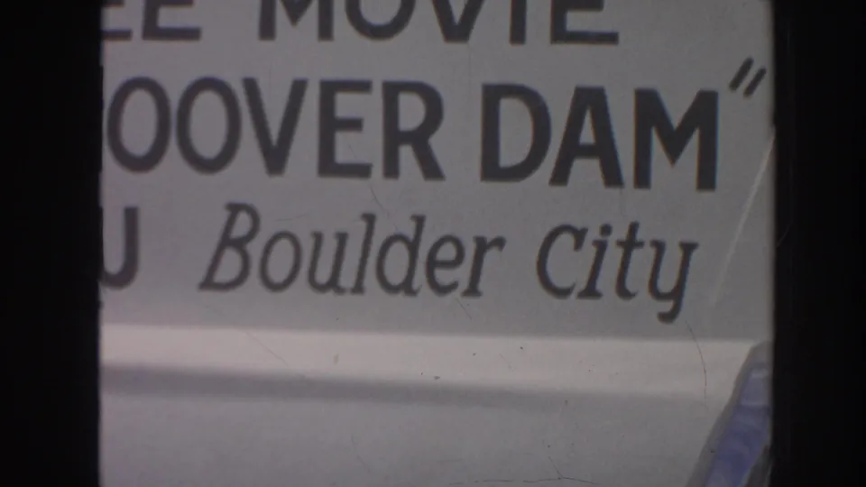 Soft 8mm close-up of cropped signage with Hoover Dam and Boulder City text, framed by dark film edges.