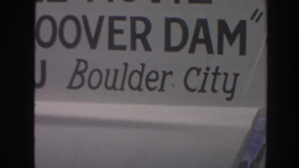 Final 1962 8mm frame holds on cropped Hoover Dam and Boulder City tourist signage with soft focus and visible film wear.