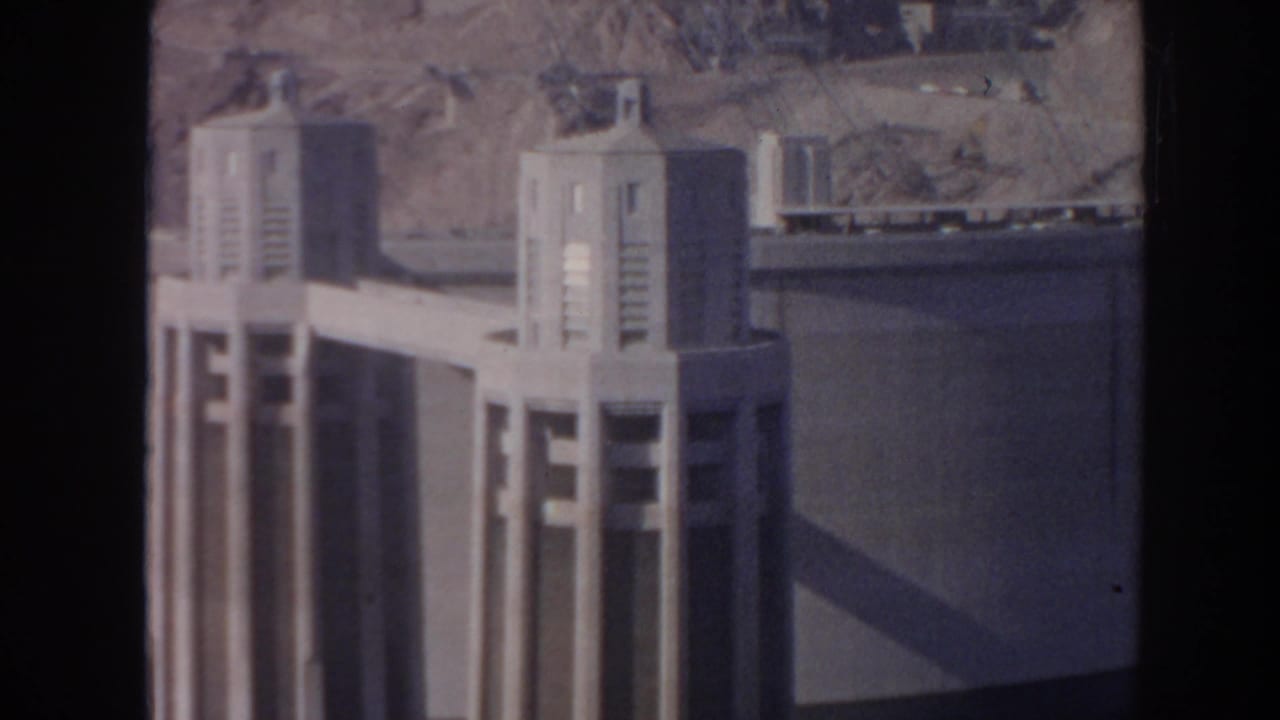 Concrete Hoover Dam tower beside a curved dam wall and reservoir water.