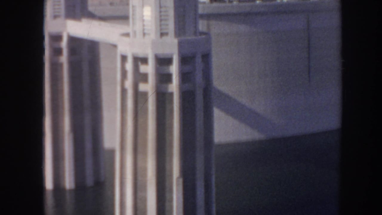 1962 Hoover Dam footage with a pale concrete tower filling the frame and a large shadow crossing the dam face.